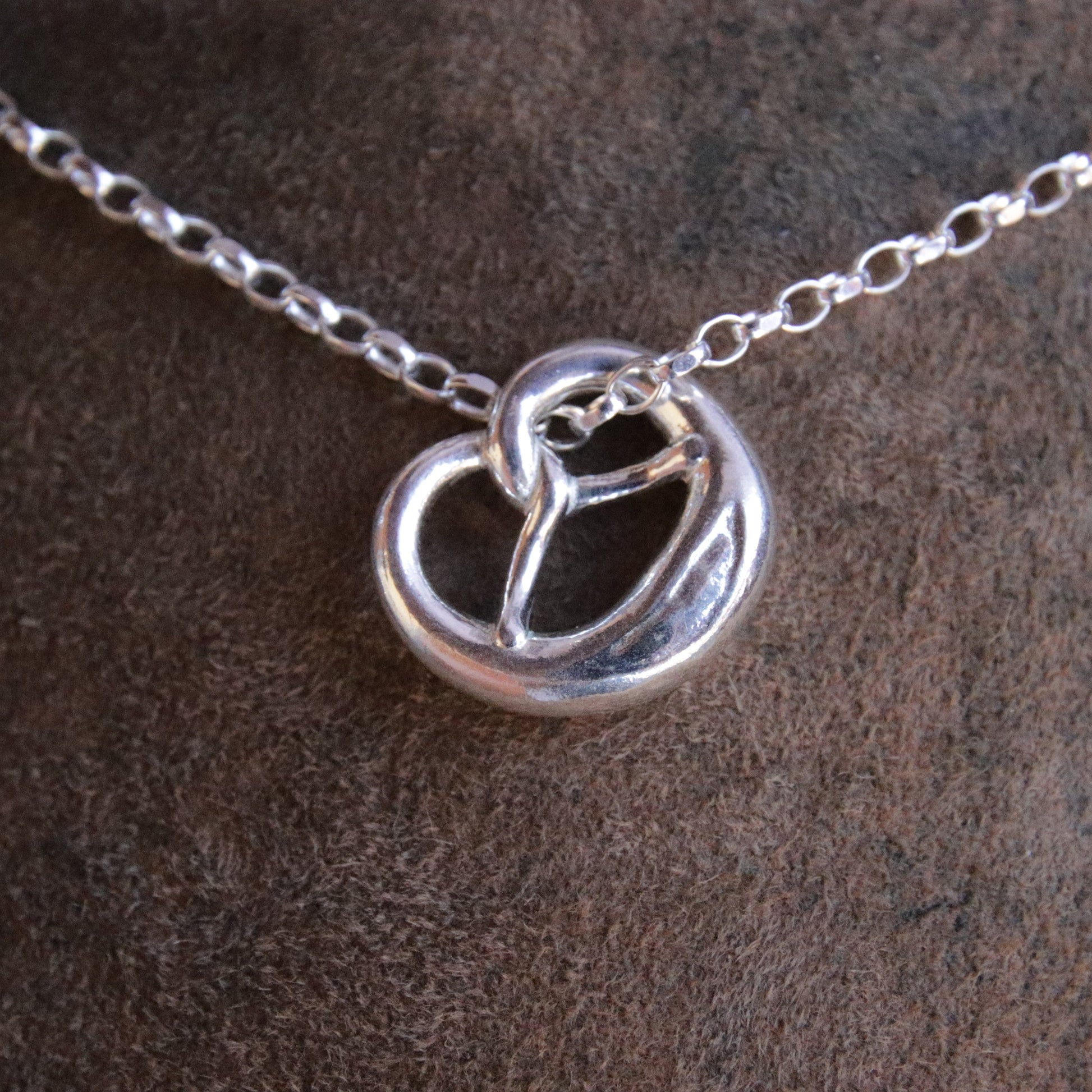 Brezn-Anhänger aus Argentium 940 Silber mit Silberkette auf Lederhosen-Leder